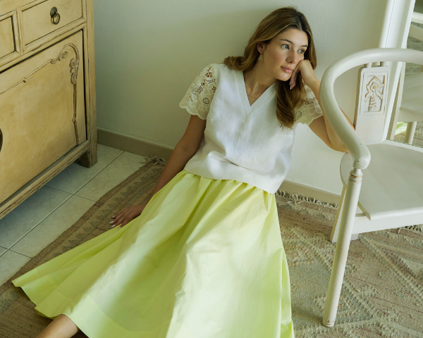 Woman in a white top and yellow skirt sitting on a chair in a roomslider_item_eTbYn8