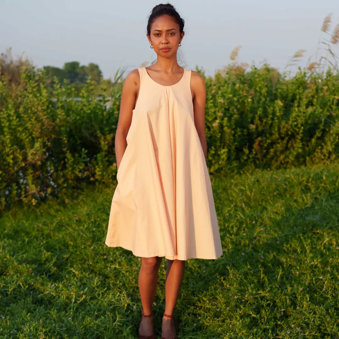 Knee-length dress in gentle peach is crafted from GOT- Certified organic cotton. SUSTAINABLY U.