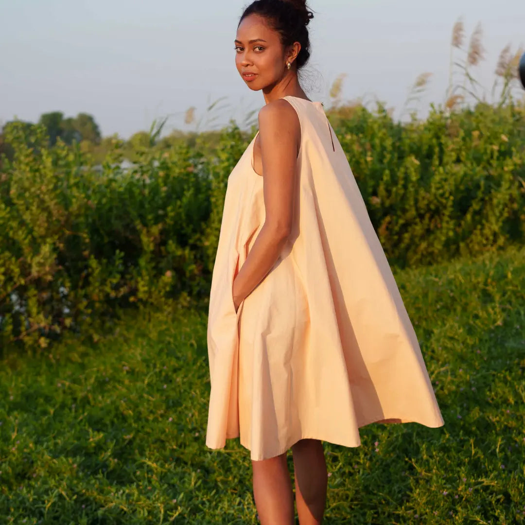 Knee-length dress in gentle peach is crafted from GOT- Certified organic cotton. SUSTAINABLY U.