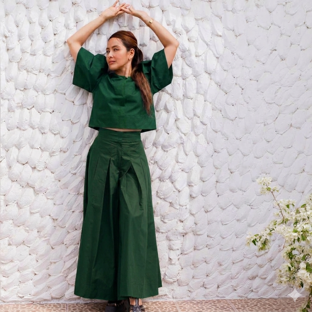 tulip dark green two-piece outfit consisting of a short-sleeve cropped top and matching high-waisted wide-leg pleated pants, posing against a textured white wall.