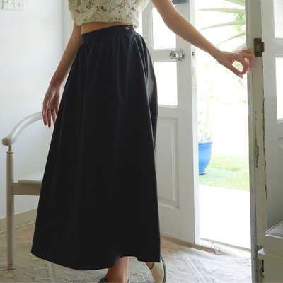 Shama black organic cotton midi skirt styled with white top, seated view
