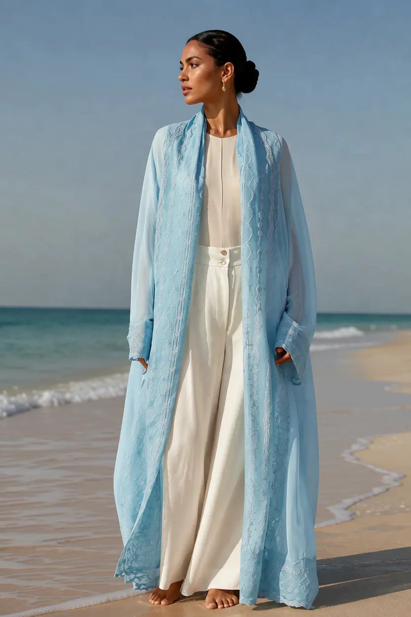 An oversized, floor-length shawl abaya crafted from premium Italian linen, featuring soft pastel hues and delicate thread work trim along the neckline, sleeves, and hem.