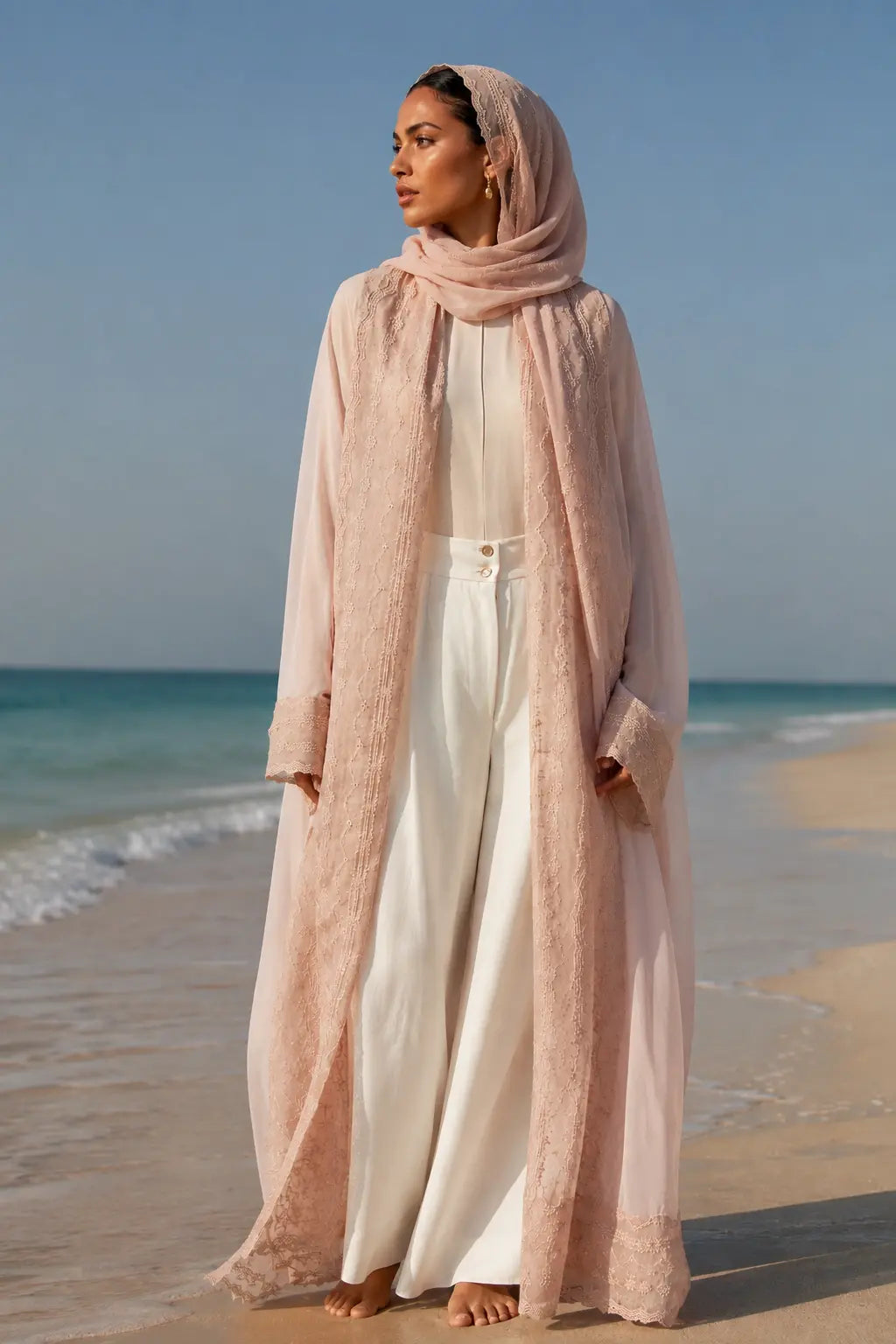 An oversized, floor-length shawl abaya crafted from premium Italian linen, featuring soft pastel hues and delicate thread work trim along the neckline, sleeves, and hem.